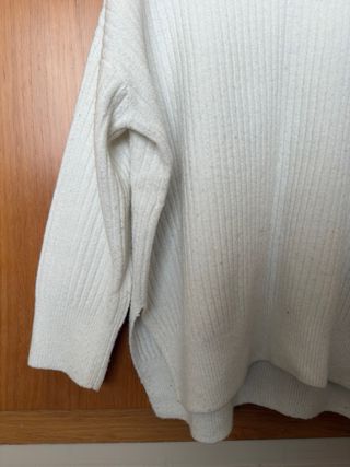 Suéter blanco alargado con cuello alto.