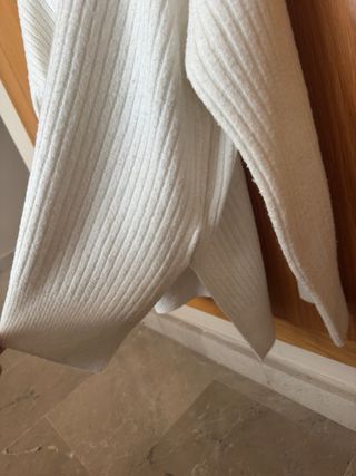 Suéter blanco alargado con cuello alto.