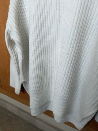 Suéter blanco alargado con cuello alto.