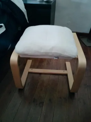 Taburete madera con cojín beige acolchado.