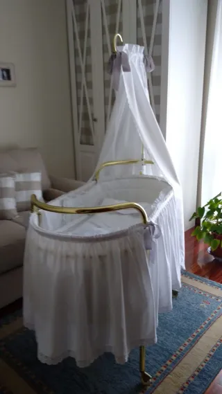 Cuna antigua con dosel y estructura dorada.