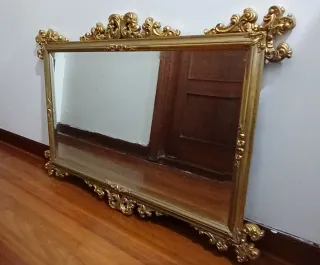 Espejo antiguo dorado con marco ornamental.