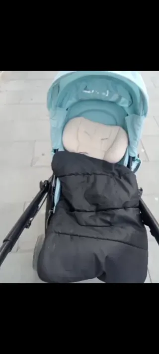 Carro de bebé azul con saco negro