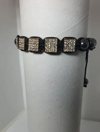 Pulsera negra con detalles dorados y cristales
