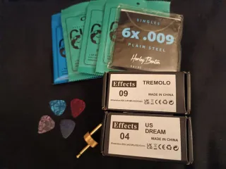 Pedales guitarra, cuerdas + púas y conector.