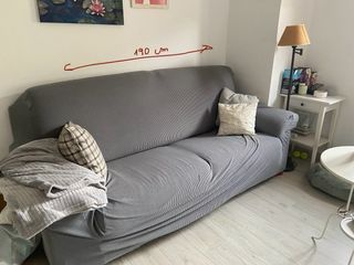 Sofá de tela naranja 3 plazas, con funda gris.