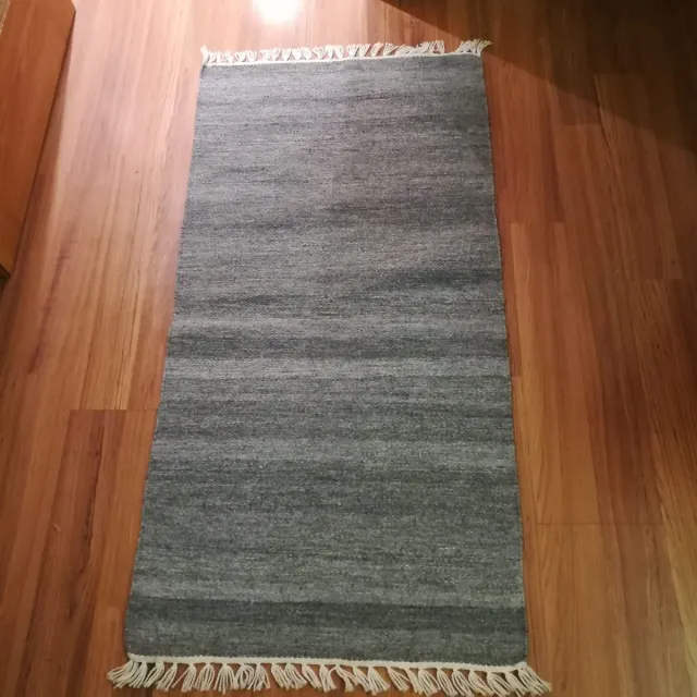 Alfombra gris de tela con flecos