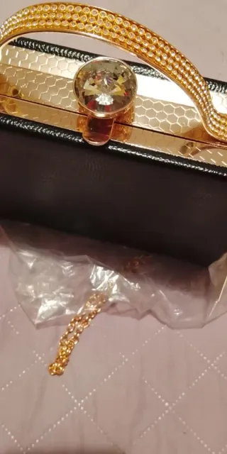 Bolso de mano dorado y negro con pedrería