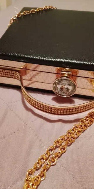 Bolso de mano dorado y negro con pedrería