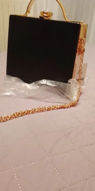 Bolso de mano dorado y negro con pedrería