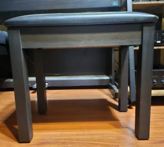 Banco de piano oscuro y acolchado.