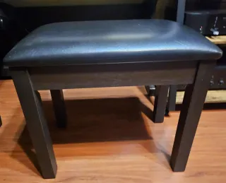 Banco de piano oscuro y acolchado.