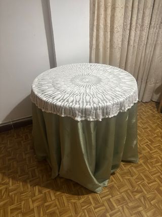 Mesa redonda con mantel verde y encaje