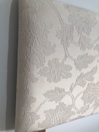 Cabecero de tela beige con bordado floral.