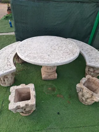 Mesa y bancos de piedra con maceteros