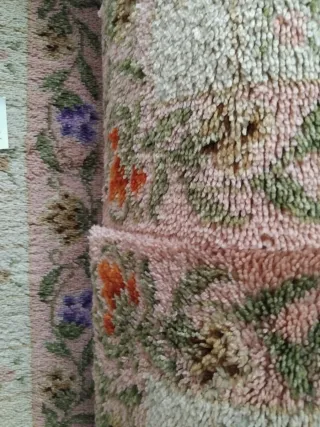 Alfombra de lana rosa con flores como nuevas.