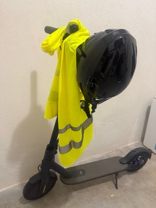 Patinete eléctrico con casco y chaleco flúor.