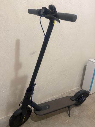 Patinete eléctrico con casco y chaleco flúor.