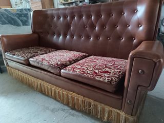 Sofá de piel marrón con cojines de estampado flora