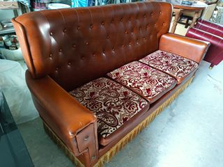 Sofá de piel marrón con cojines de estampado flora