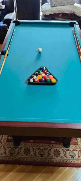 Mesa de billar , con tres palos y las bolas .