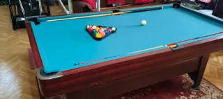 Mesa de billar , con tres palos y las bolas .