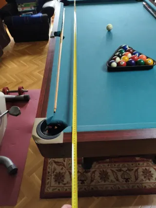 Mesa de billar , con tres palos y las bolas .