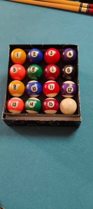 Mesa de billar , con tres palos y las bolas .