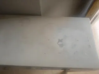 Mesa de entrada blanca con cajones gris.