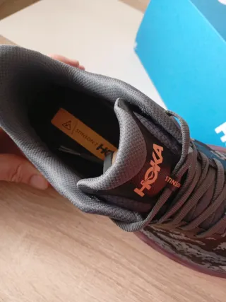 Zapatillas Hoka grises y naranjas