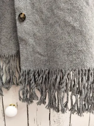 Chaqueta de paño gris con flecos.
