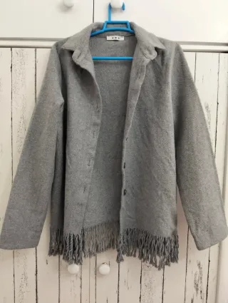 Chaqueta de paño gris con flecos.