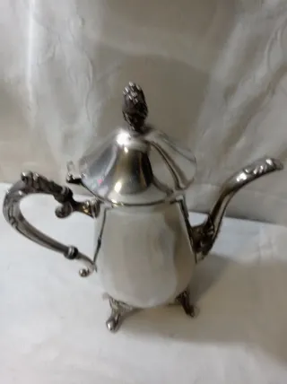 Jarra de metal plateado con patas