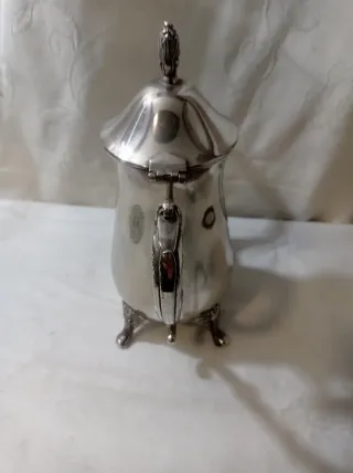 Jarra de metal plateado con patas