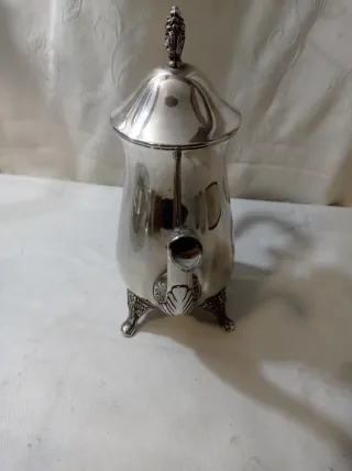 Jarra de metal plateado con patas