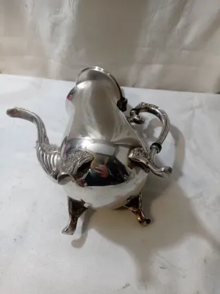 Jarra de metal plateado con patas