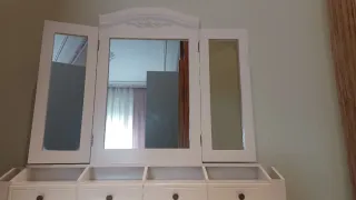 Tocador blanco con espejo y taburete.