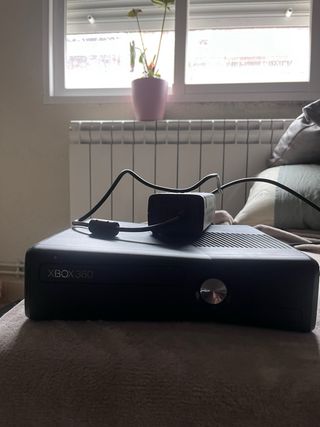 Xbox 360 Negra con su enchufe.