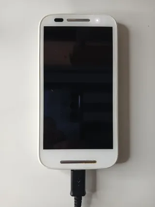 Teléfono blanco más cable de carga y auriculares.