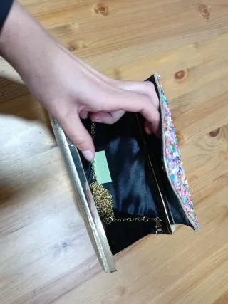 Bolso de mano dorado con pedrería multicolor