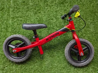 Bicicleta Btwin sin pedales roja con freno.