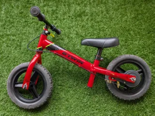 Bicicleta Btwin sin pedales roja con freno.