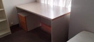 Escritorio grande beige con cajonera.