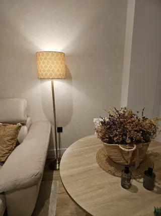 Lámpara de pie dorada con pantalla textil .