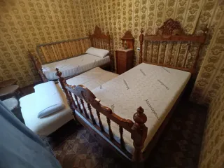 Cama antigua de madera con mesita y dos sillas