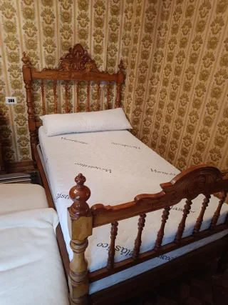Cama antigua de madera con mesita y dos sillas