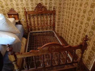 Cama antigua de madera con mesita y dos sillas