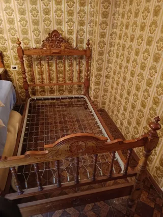 Cama antigua de madera con mesita y dos sillas