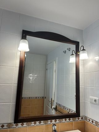 Espejo con marco de madera para baño con lámparas.