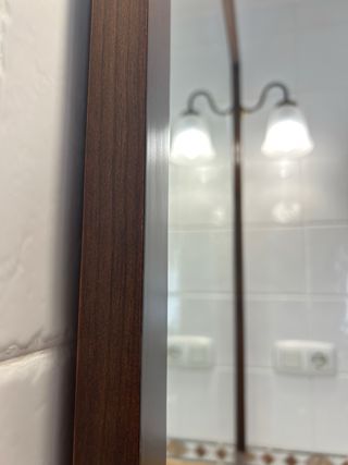 Espejo con marco de madera para baño con lámparas.